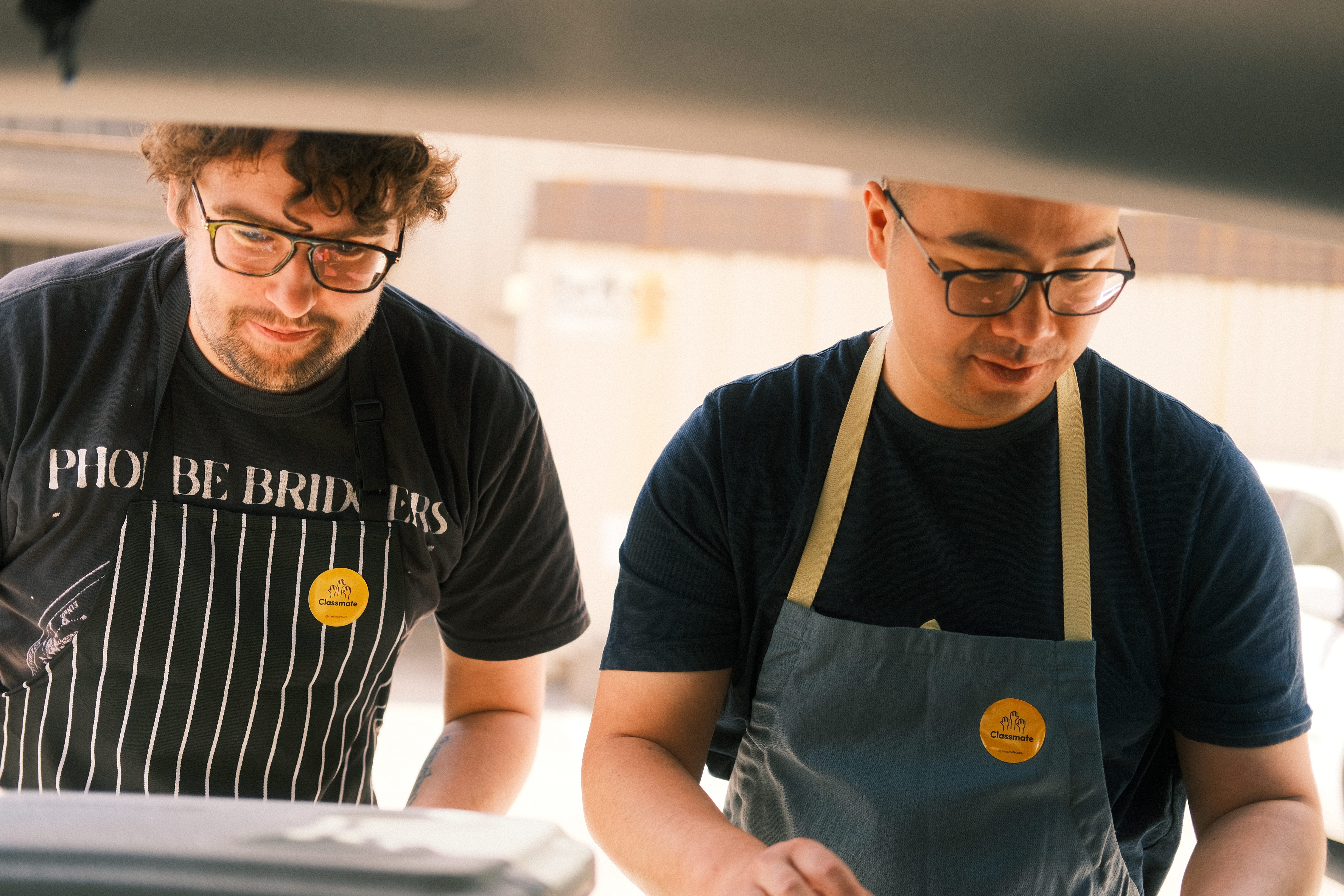 Two handsome gentlemen sorting ice cream in the trunk of their car.