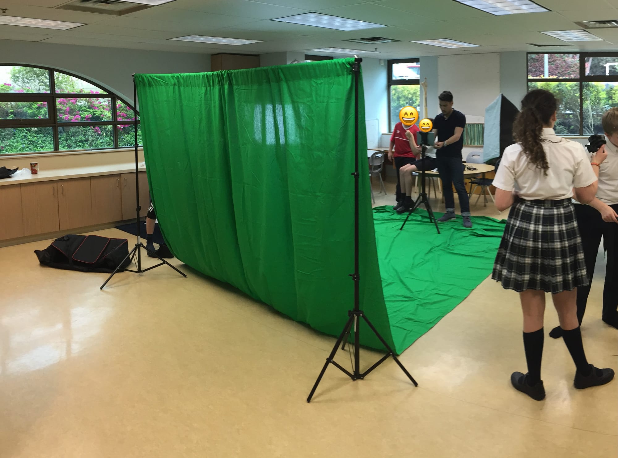 A lively room of students working on filming on a green screen.
